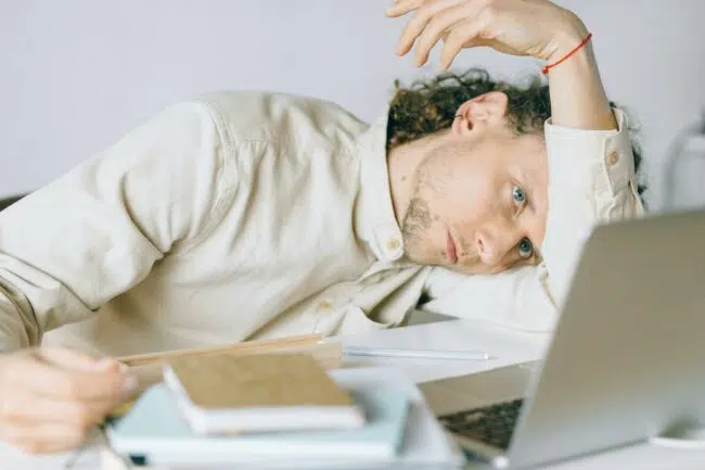A male burnt out with his head down on a book exhausted.