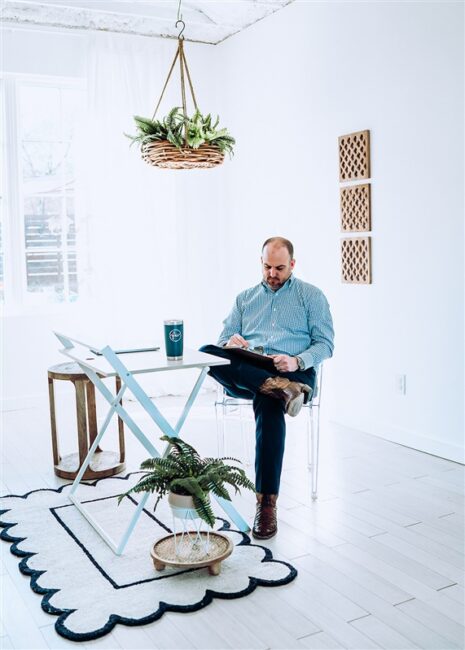 Rane Wallace sitting on a chair and taking notes.